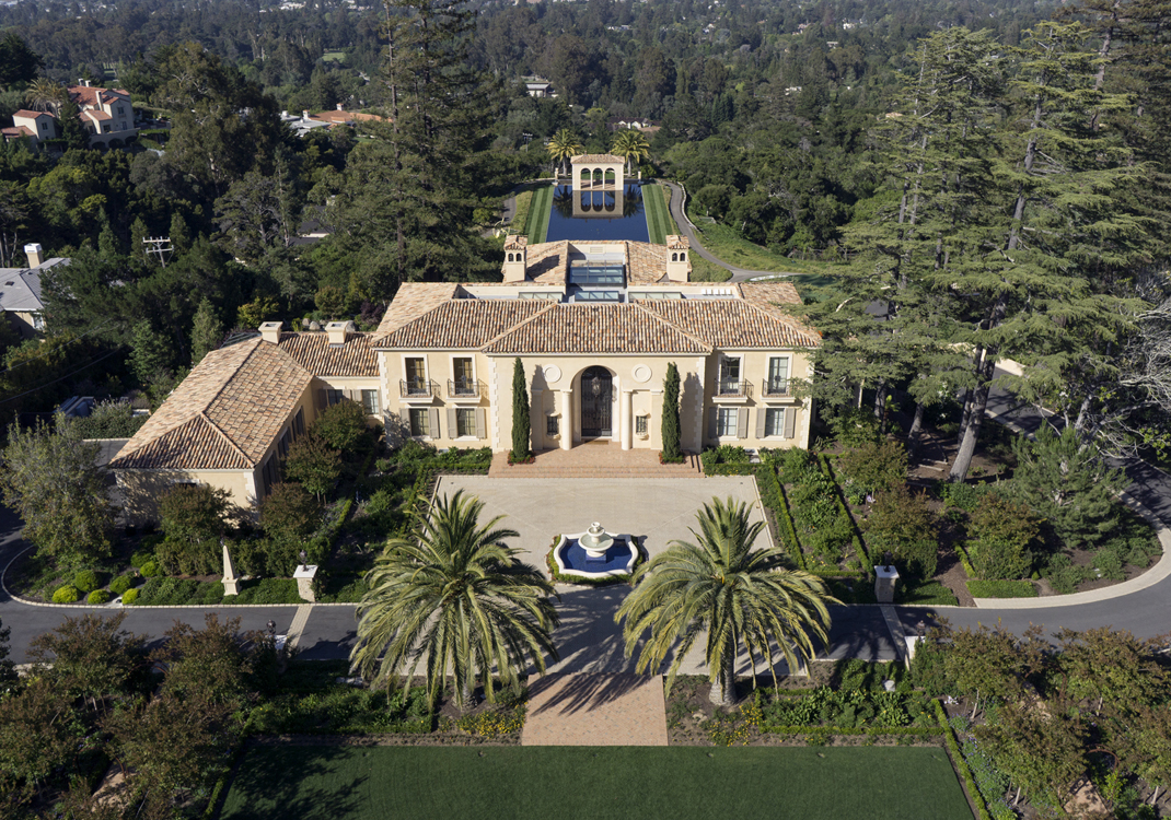 This Spanish revival villa is situated in a 13 acre garden which cascades down a steep hillside into a ravine and up the other side. Buildings were placed on steep slopes, allowing the flat space in the center for the formal entry garden and lawn. The ramparts of the rear garden step down the hillside and include pools, terraces, fountains, runnels and a reflecting pond, all of which terminate at the belvedere with ‘floating’ pavilion. Other garden features include; koi pond, amphitheater, sports complex and specialty gardens. 