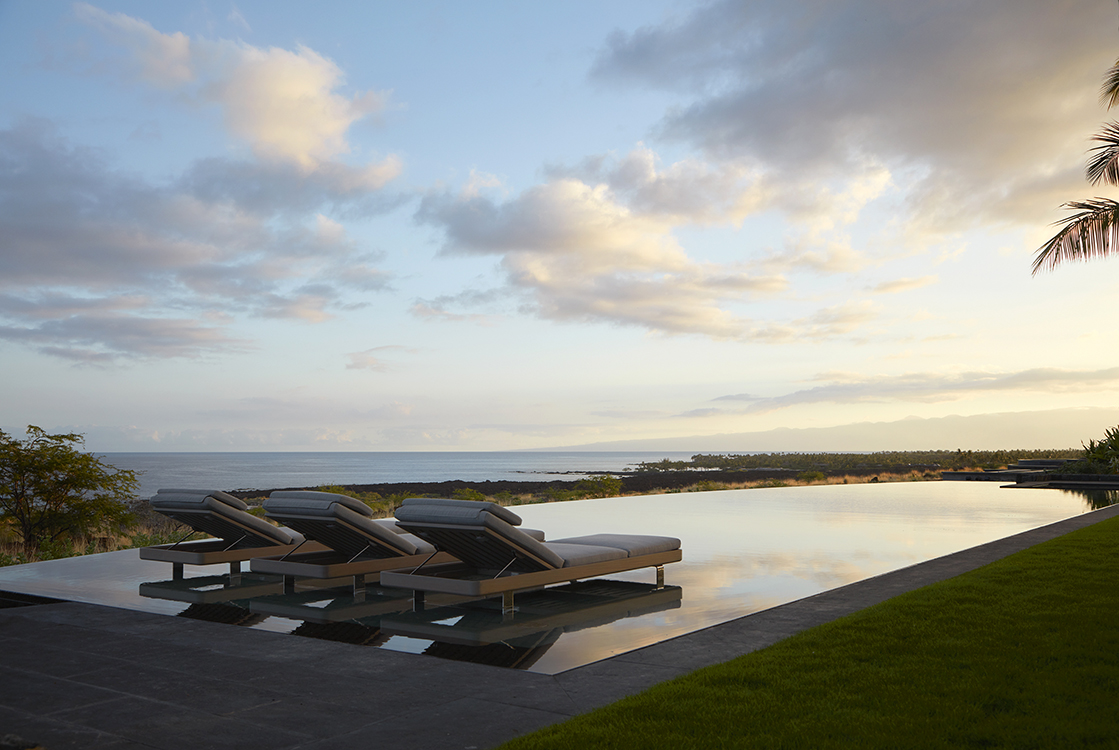 The project is a modern interpretation of a bungalow garden. The design is restrained and uses understated materials. The shower gardens have glass walls and shelves that give privacy and provide lighting. The pool is lined in green marble and includes a wet shelf for sunbathing. The planting palette is lush within the walls and dry as it meets the natural landscape.