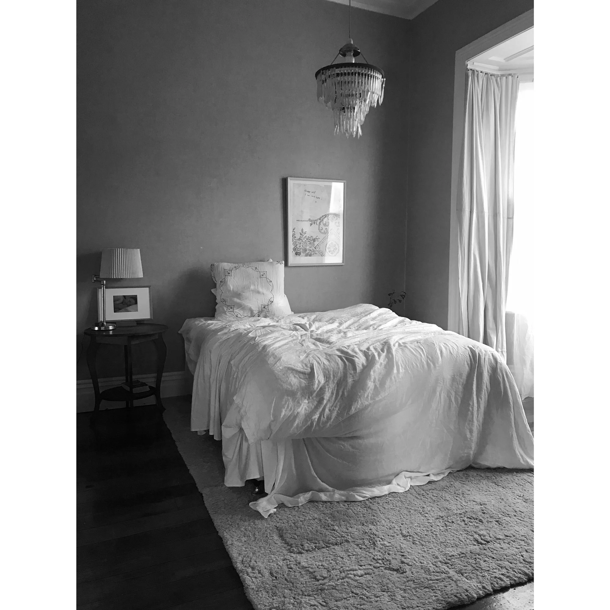 Installation view of the bedroom of  A private view , with  sleep well I'm still here, x  on the wall above the bed.