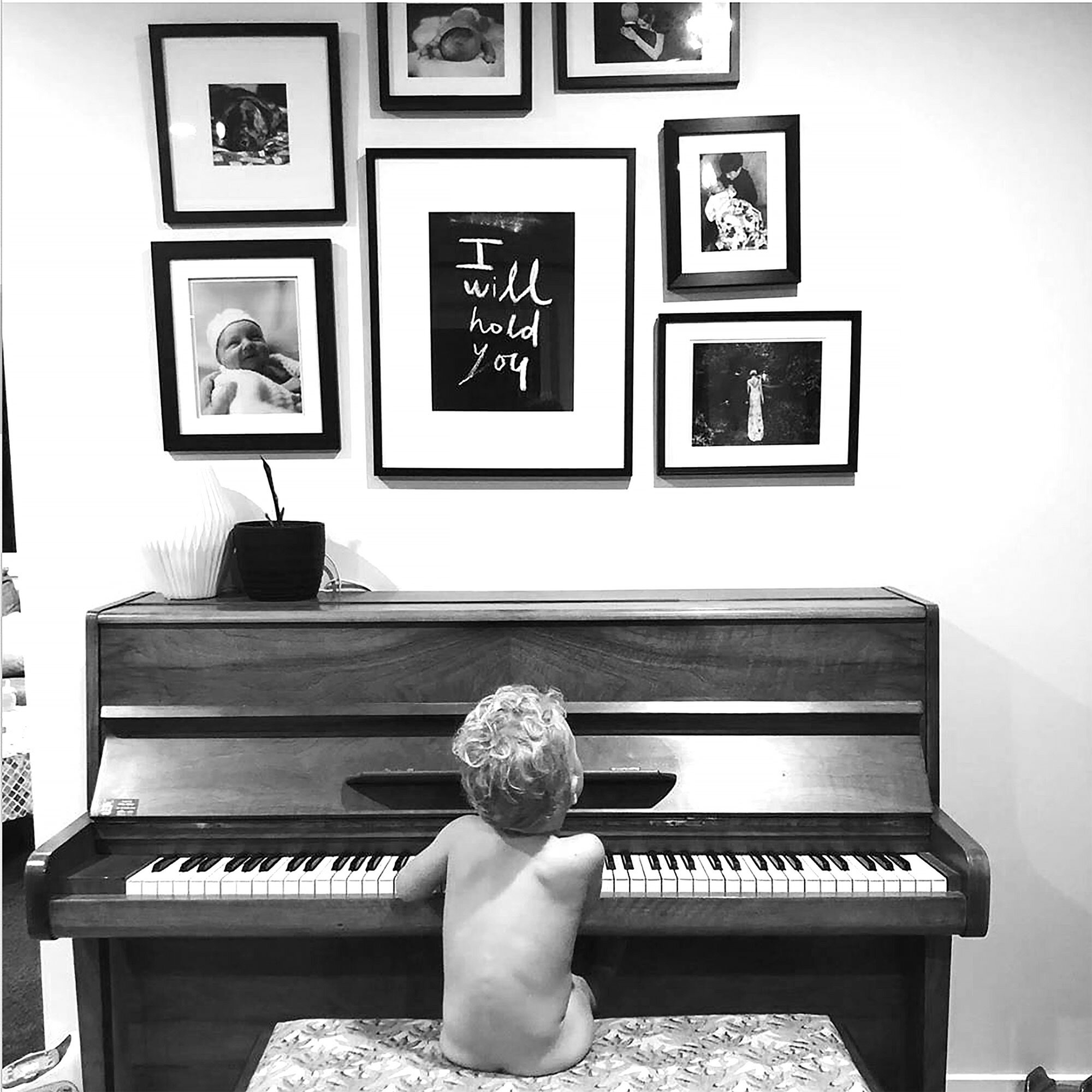  A small framed studioprint of     I will hold you, 2019   sits nestled within a salon hang of precious memories.  Photograph sent to me by the mum of the beautiful child sitting dreaming at the piano.  