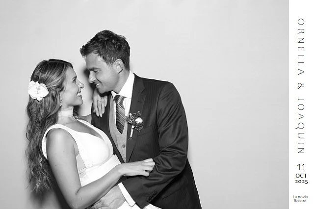 Una pareja en una boda, con la novia vestida de blanco y el novio de traje, mirándose sonrientes.