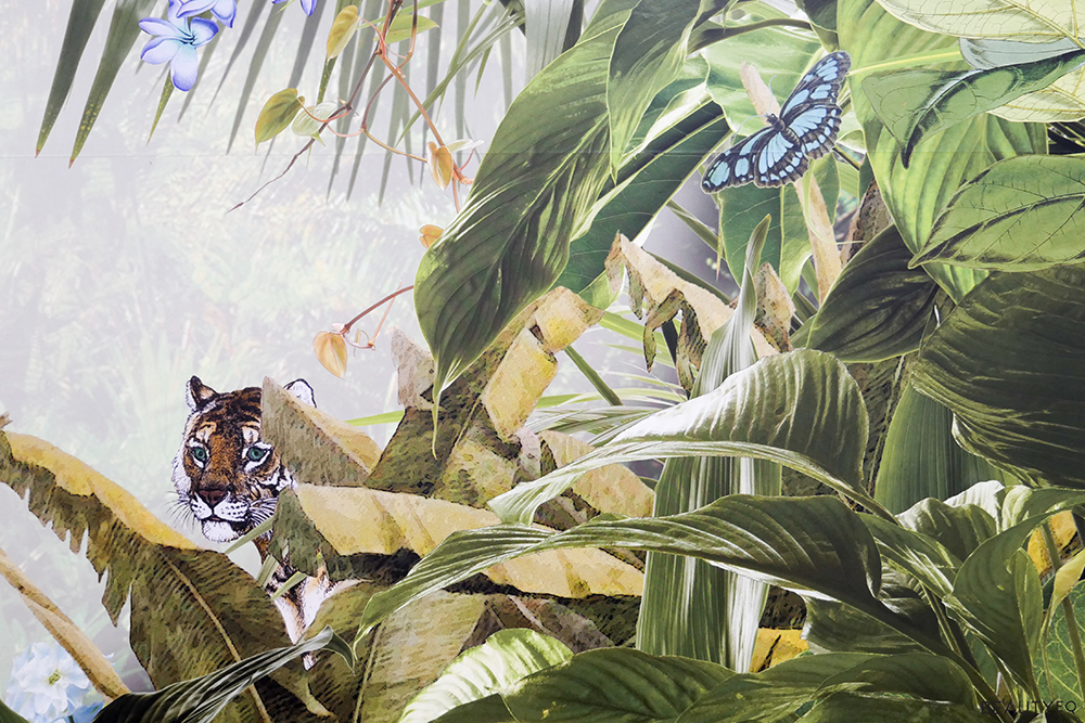 A jungle themed wall paper with plenty of plants and a tiger emerging from them