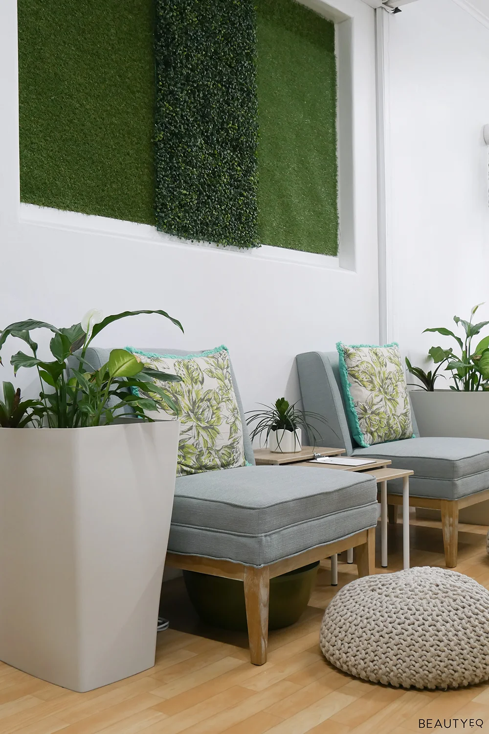 Beauty salon waiting room with blue chairs, wooden floor and plants