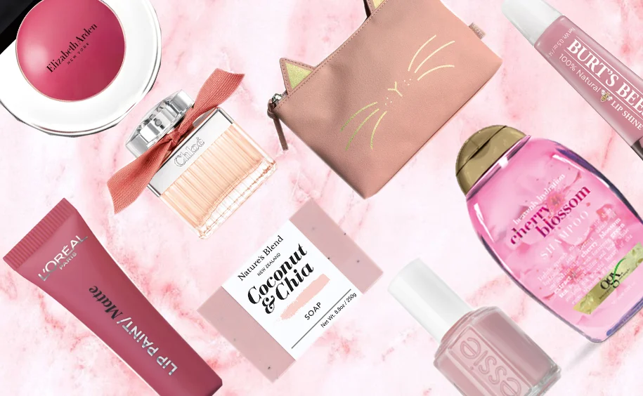 A range of different beauty and health products laid against a pink and white marble background 