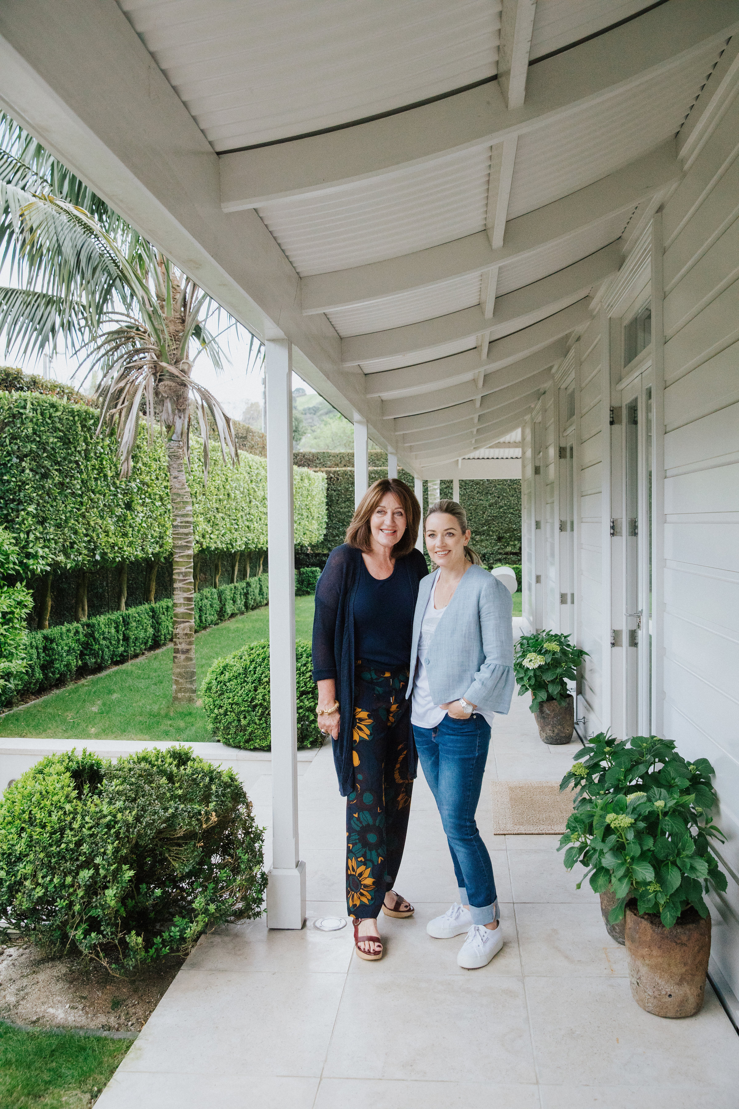 Two woman standing next to each other in the outside porch area of their home