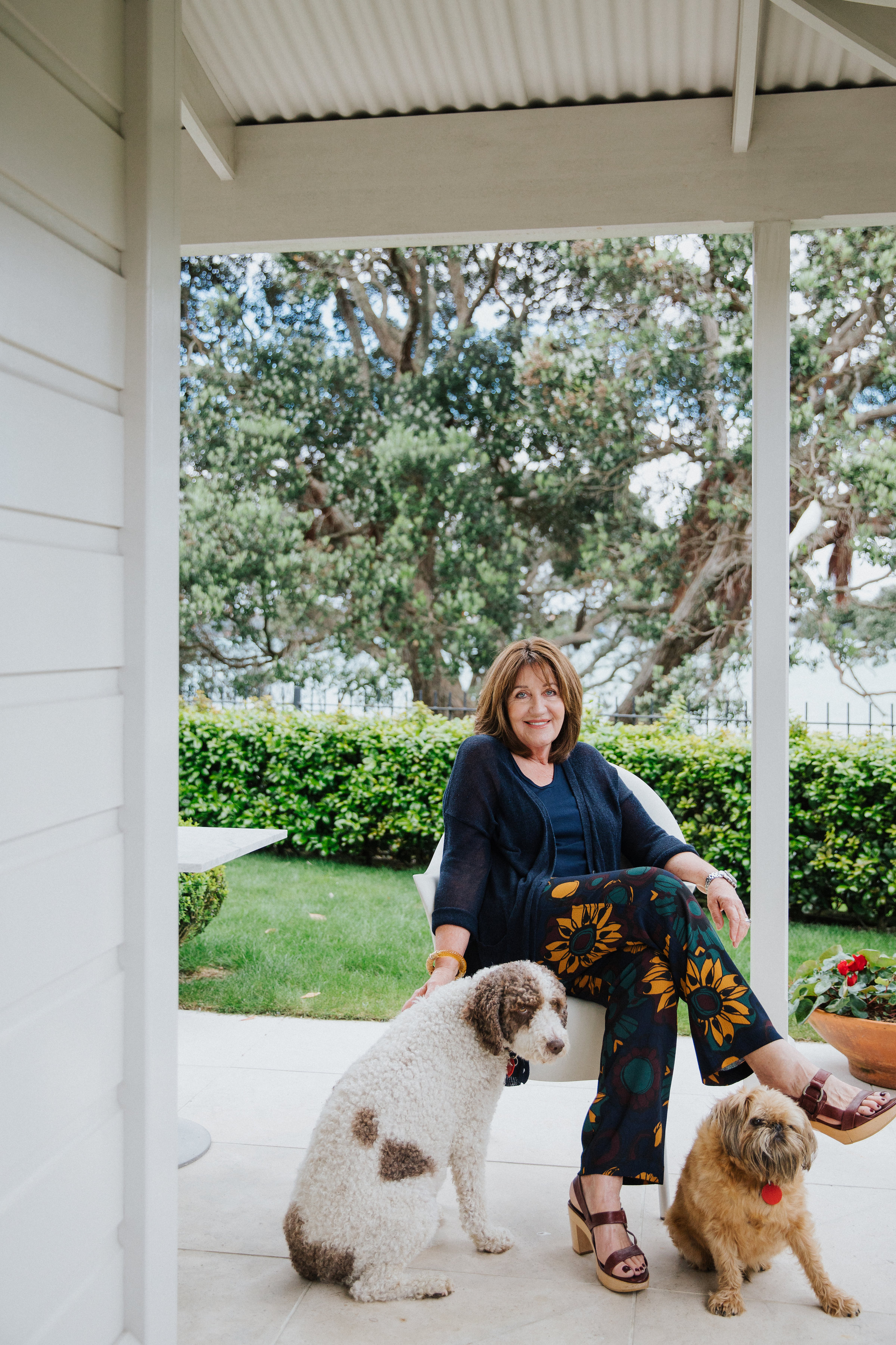 Woman sitting on white porch surrounded by dogs