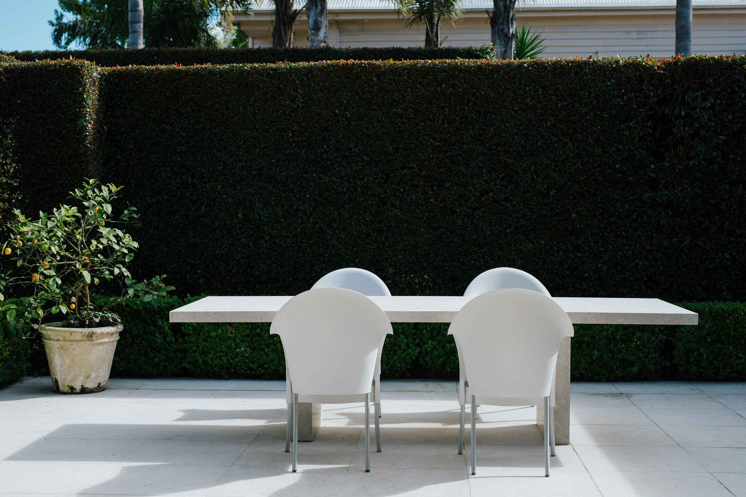 White table and chairs outside near hedge