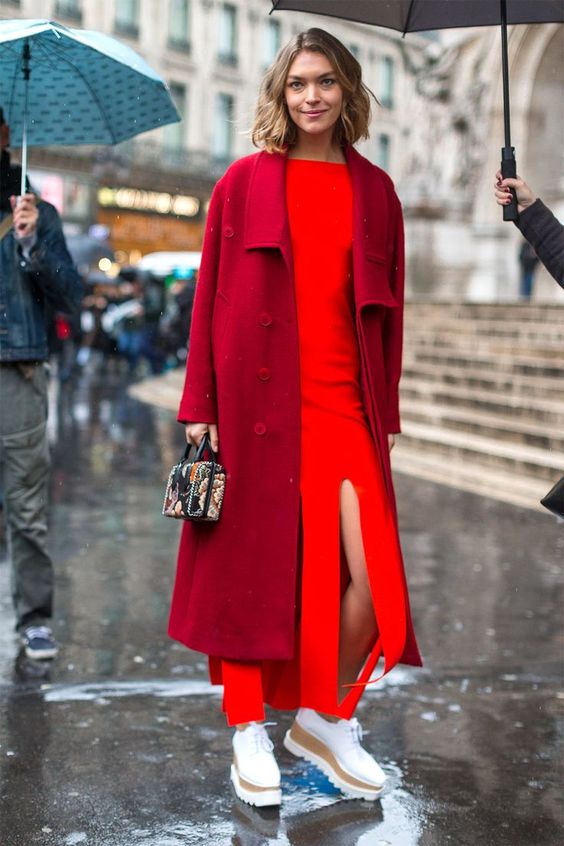 Model wearing red trench coat with red long dress and sneakers