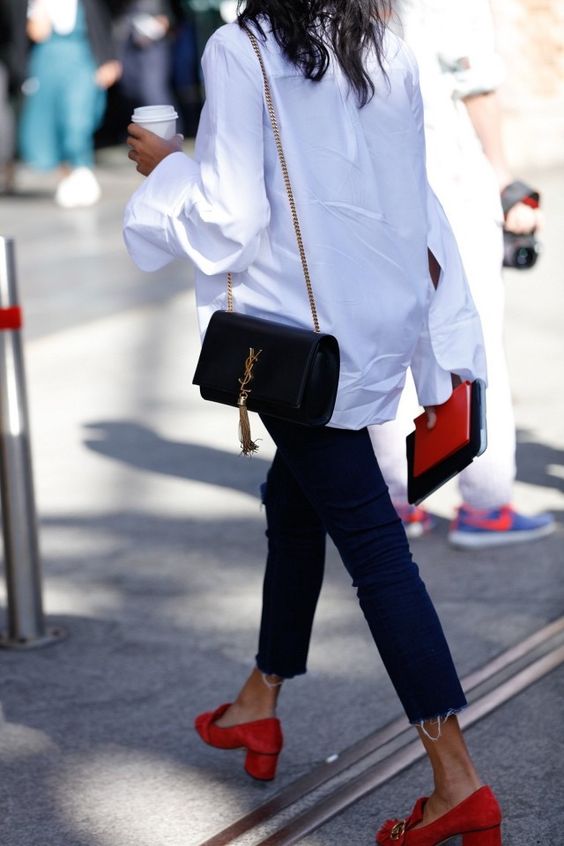 model wearing white shirt blue jeans and red heels with black bag