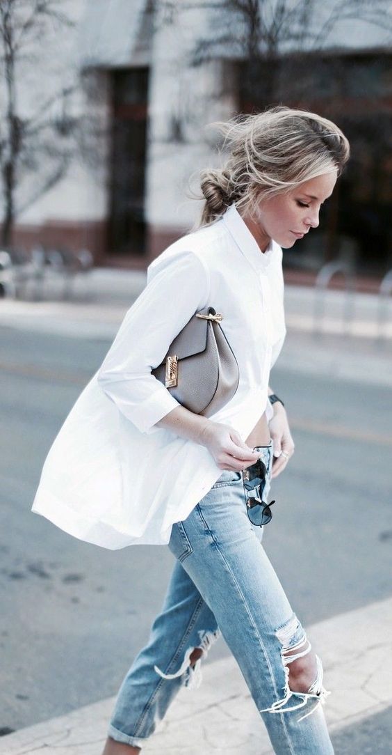 Blonde model wearing white shirt, grey bag and ripped blue jeans