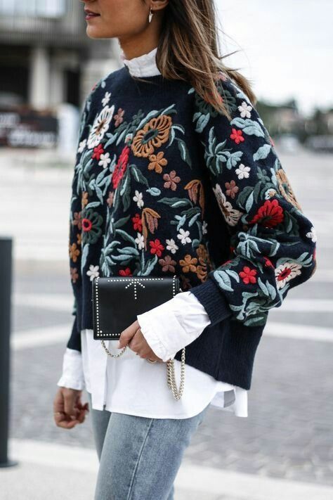 brown haired model wearing floral sweater over white shirt and ripped blue jeans