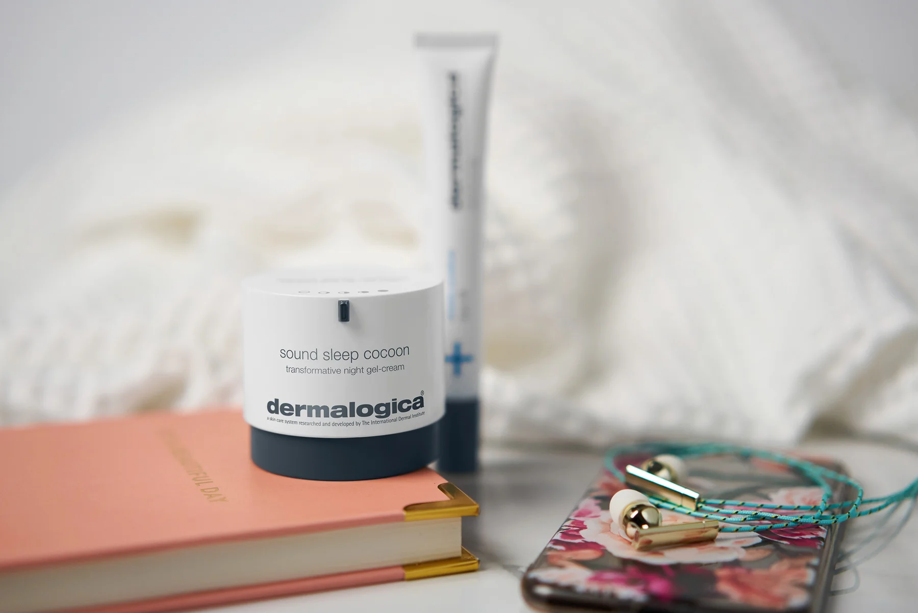 Dermalogica sound sleep cocoon products on a pink diary next to an iPhone