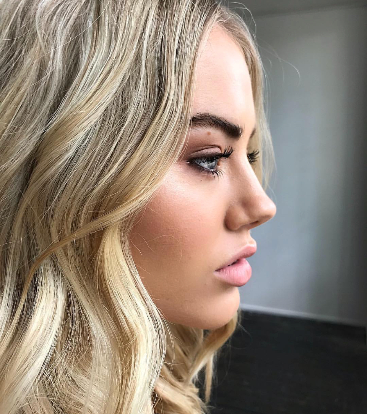 side profile shot of blonde female model with dark eyebrows