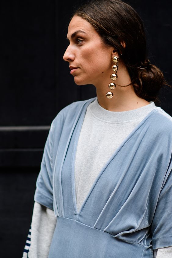 Woman with blue and white top and dangling gold bead earing