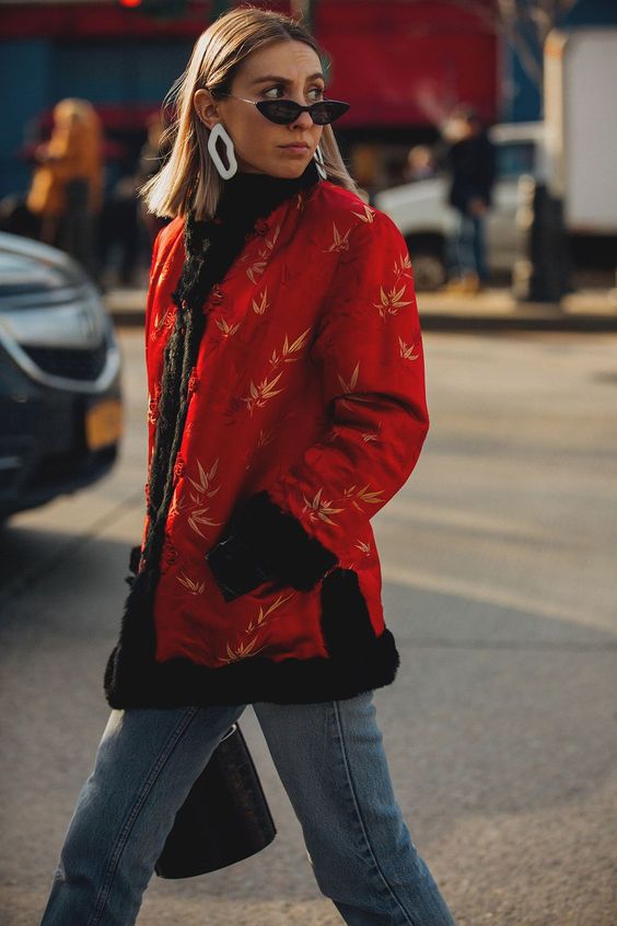 Woman in red coat and blue jeans wearing earrings