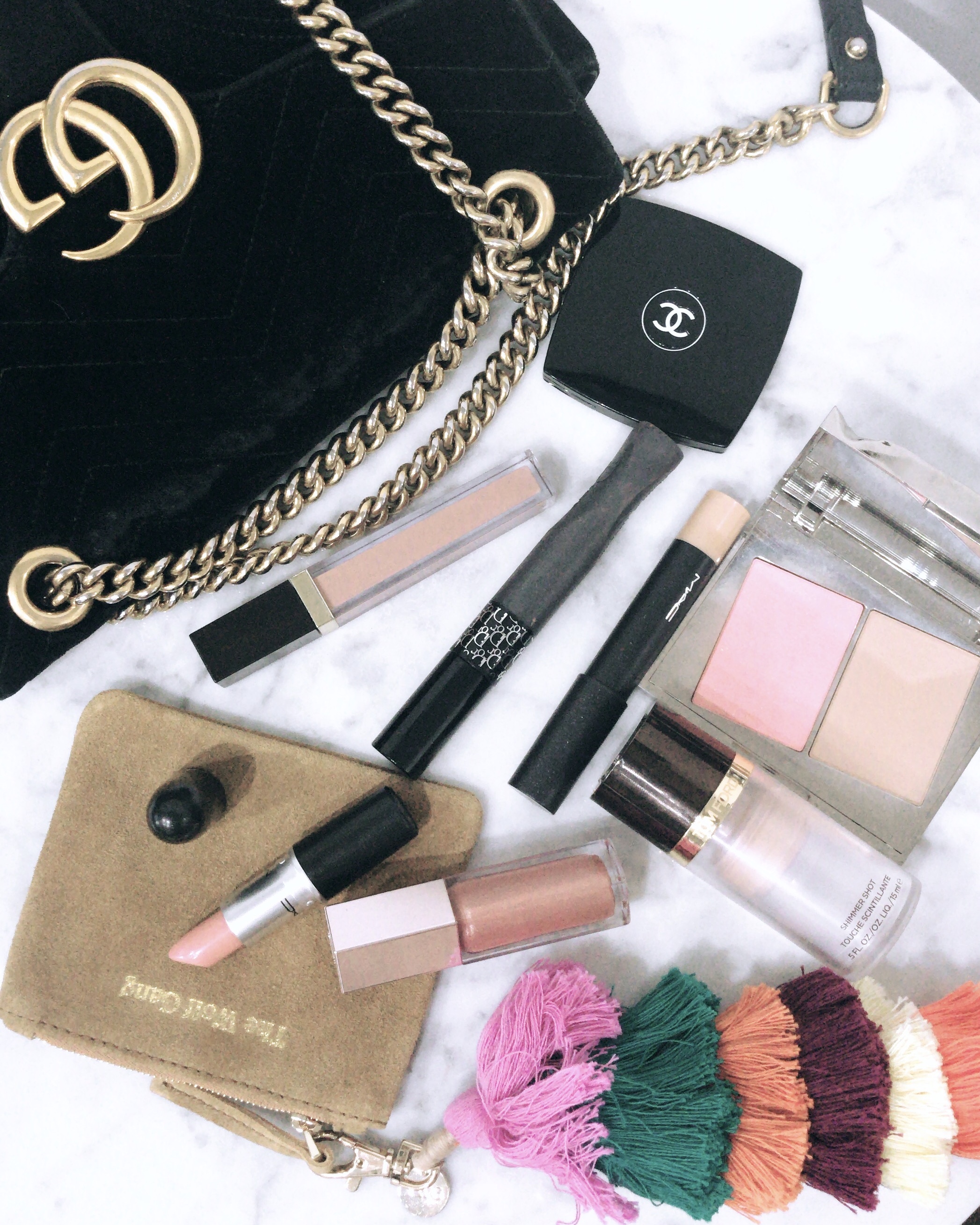 A range of make up products and fashion accessories laid out against a white background 