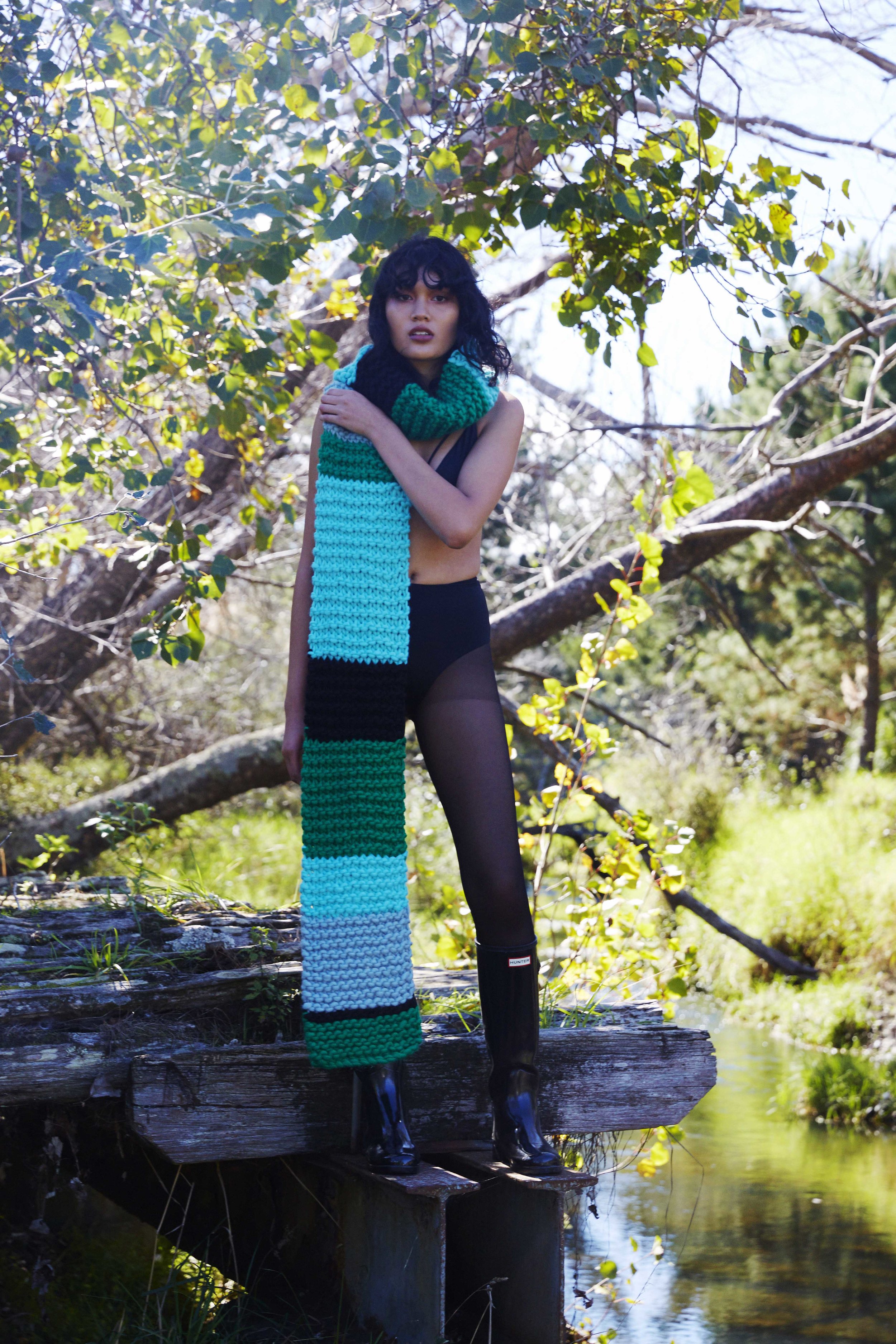 Woman in long black boots and colourful big scarf in the forest