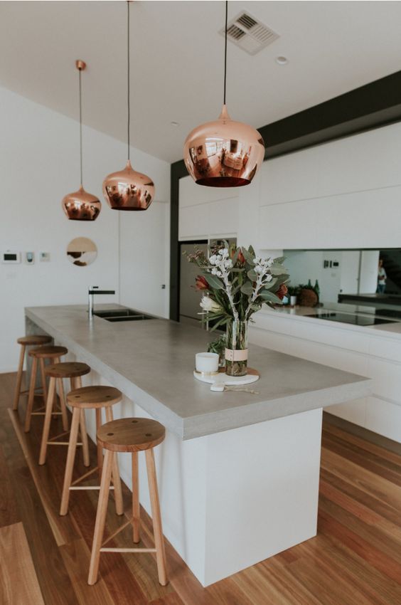 Modern kitchen with brass hanging lights and wooden stools