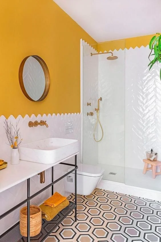 03-a-stylish-bathroom-with-a-sunny-yellow-wall-white-tiles-a-round-mirror-and-a-neutral-and-lighweight-vanity.jpg