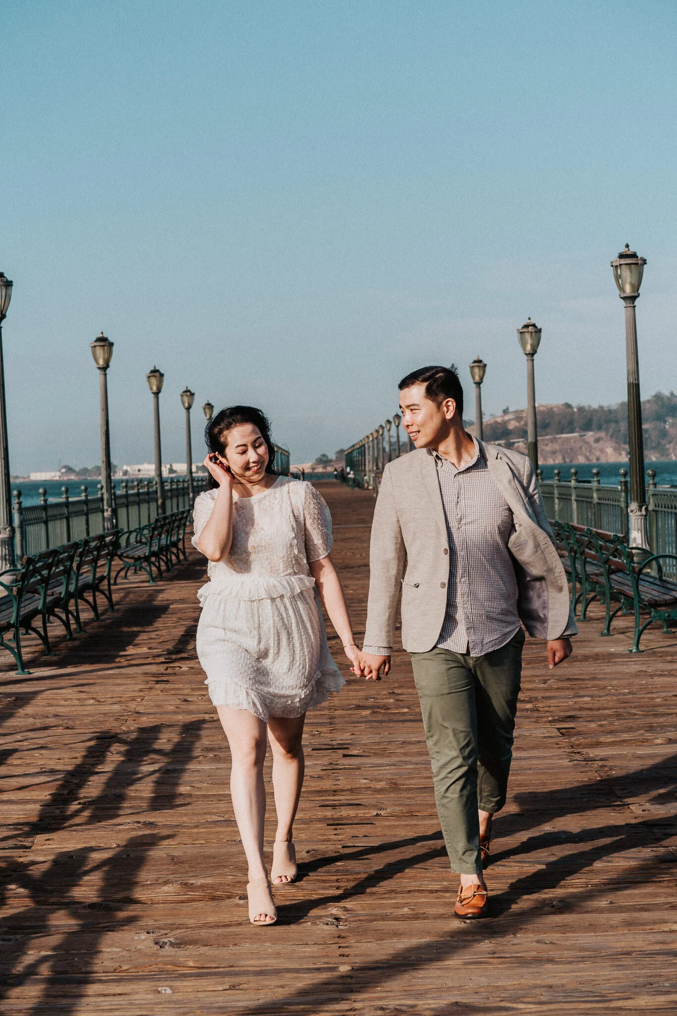 Engaged couple walking on San Francisco Pier.