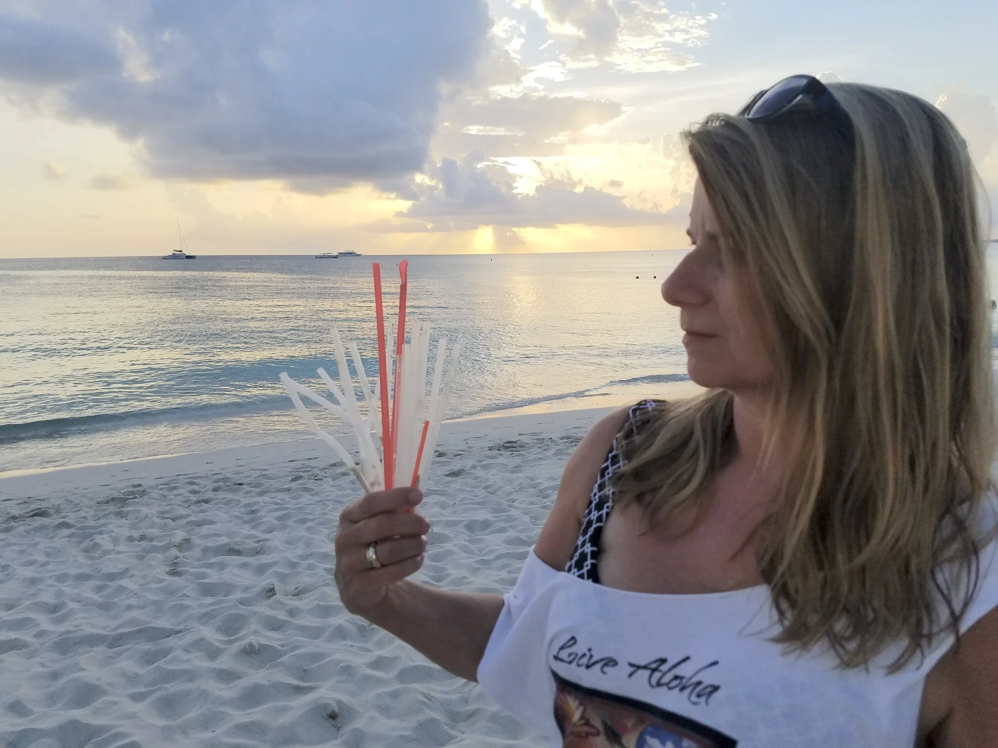 STRAWS Producer/Director Linda Booker and discarded plastic straws on Grand Cayman’s 7 mile beach.