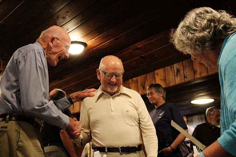 Stu Clark congratulates Paul Davis while Sue Aspelund cuts the cake.