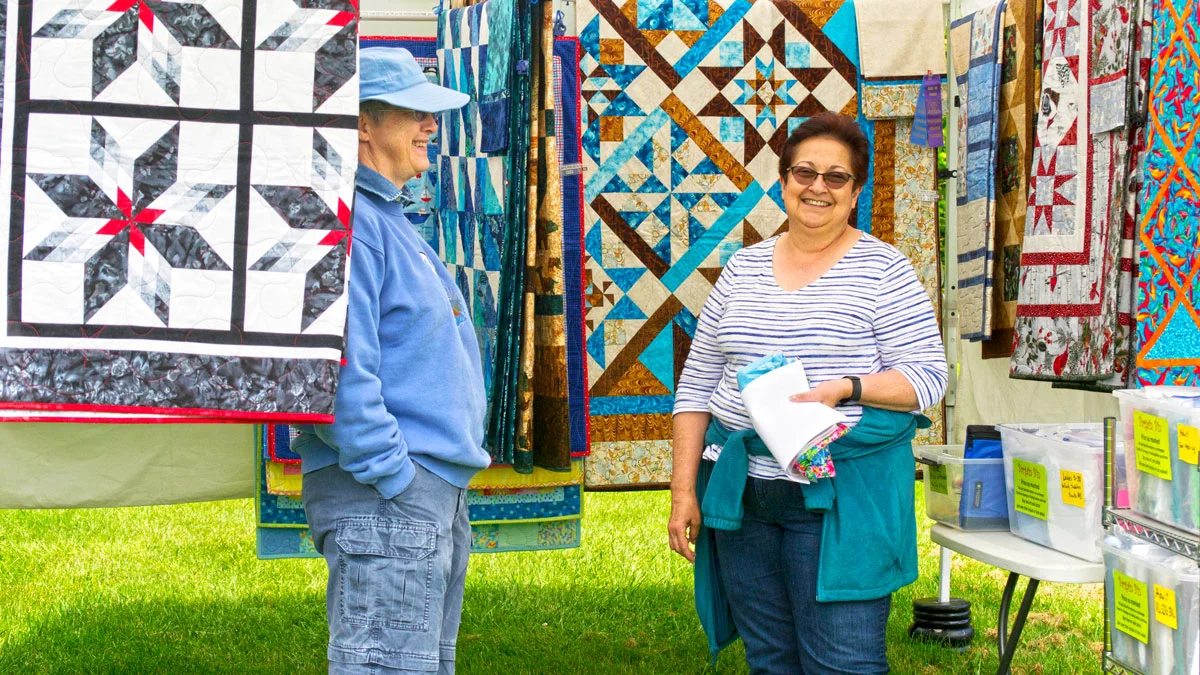 Mary Barstow (left) shows her quilts at the Saturday Market