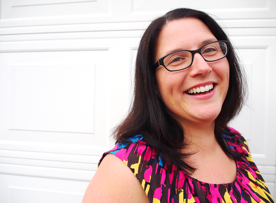 recovery coach, Misty, is smiling at the camera. She is wearing a colorful, short-sleeved shirt and has straight, shoulder-length brown hair