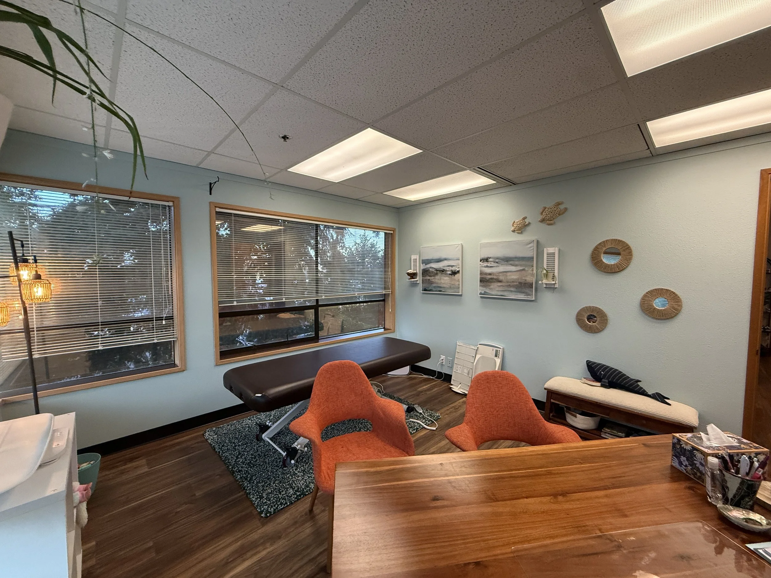 Interior of an office or meeting room with windows, artwork, and orange chairs.