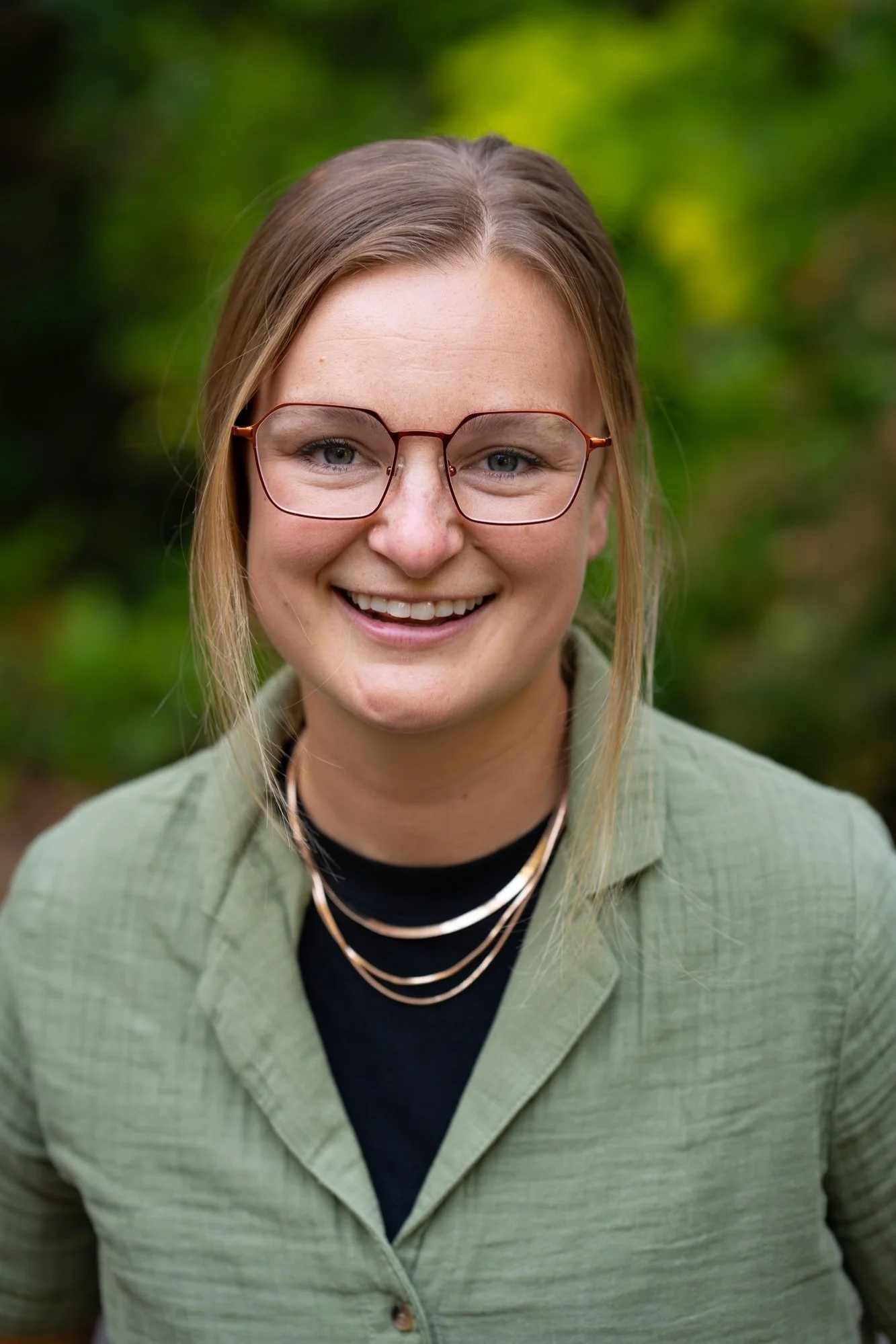 Dietitian Kellan Morgan is wearing a green blouse and stacked gold chain necklaces. She has blonde hair and is smiling