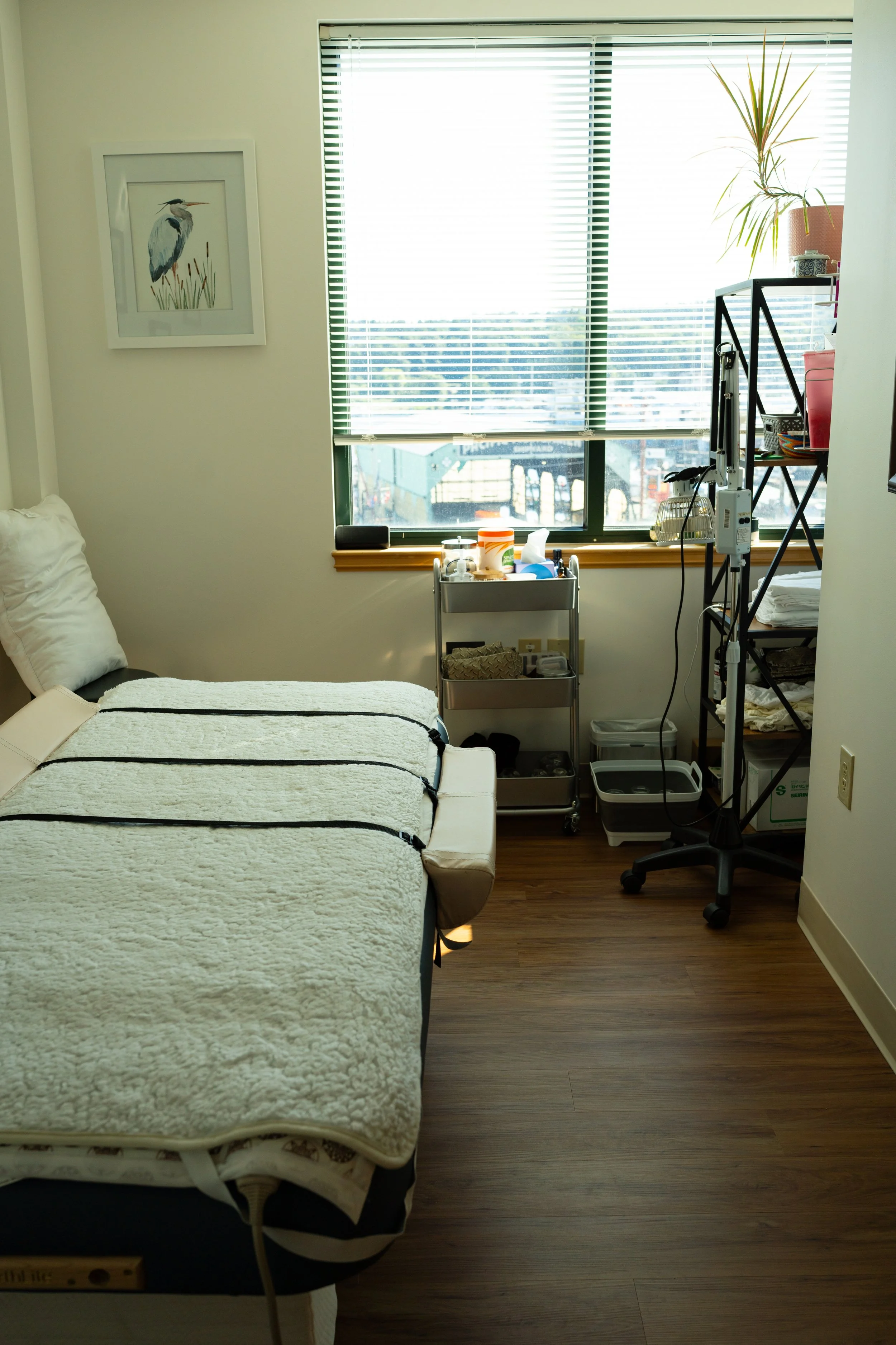 View through a doorway into an OCH exam room with chairs, a desk, and an examination table beside a window.