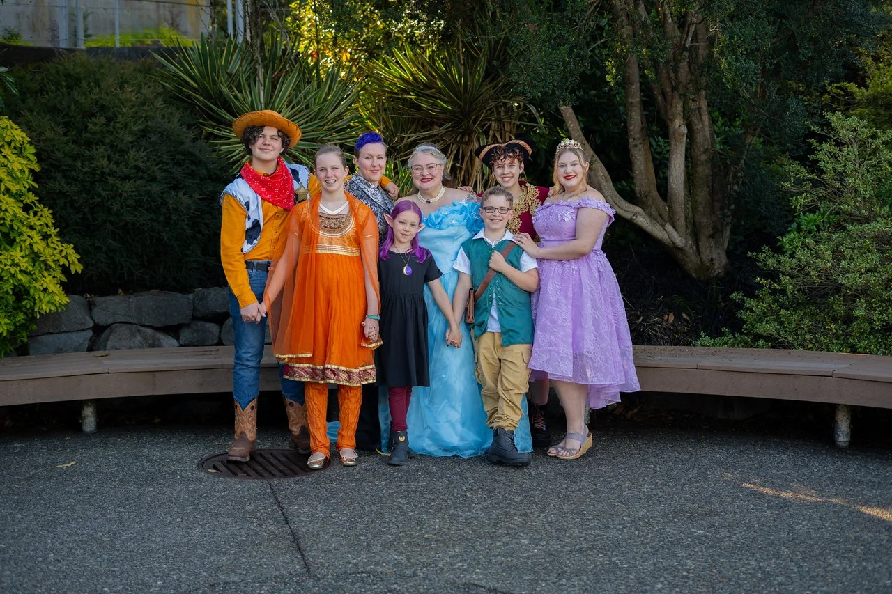 family, dressed up in Disney outfits are standing in front of greenery in Seattle