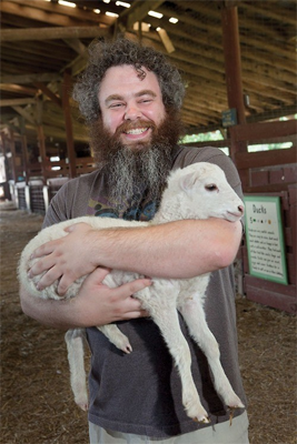 Image shows Patrick Rothfuss (A Famous Author) holding a very cute lamb.