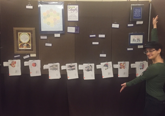 Image shows Ariela in her chibi outfit next to two panels of mostly empty pegboard. There are a few pieces of art (and lots of greeting cards), but most of what you see is brown.