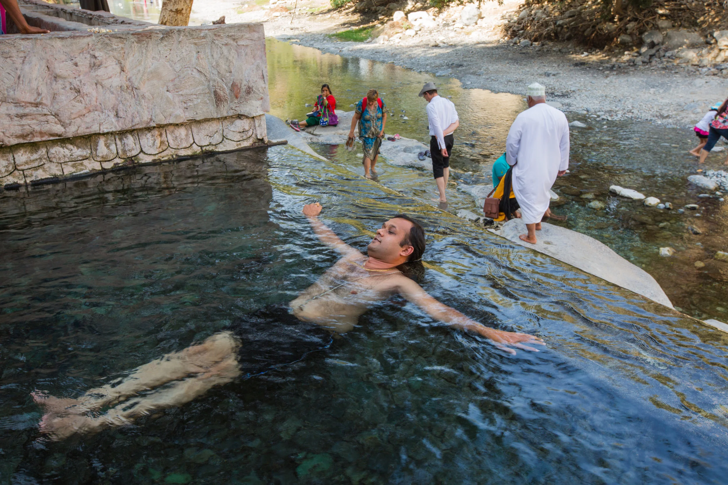  A man relaxes in the pool directly under the opening of the underwater spring, Ayn Thawara. 