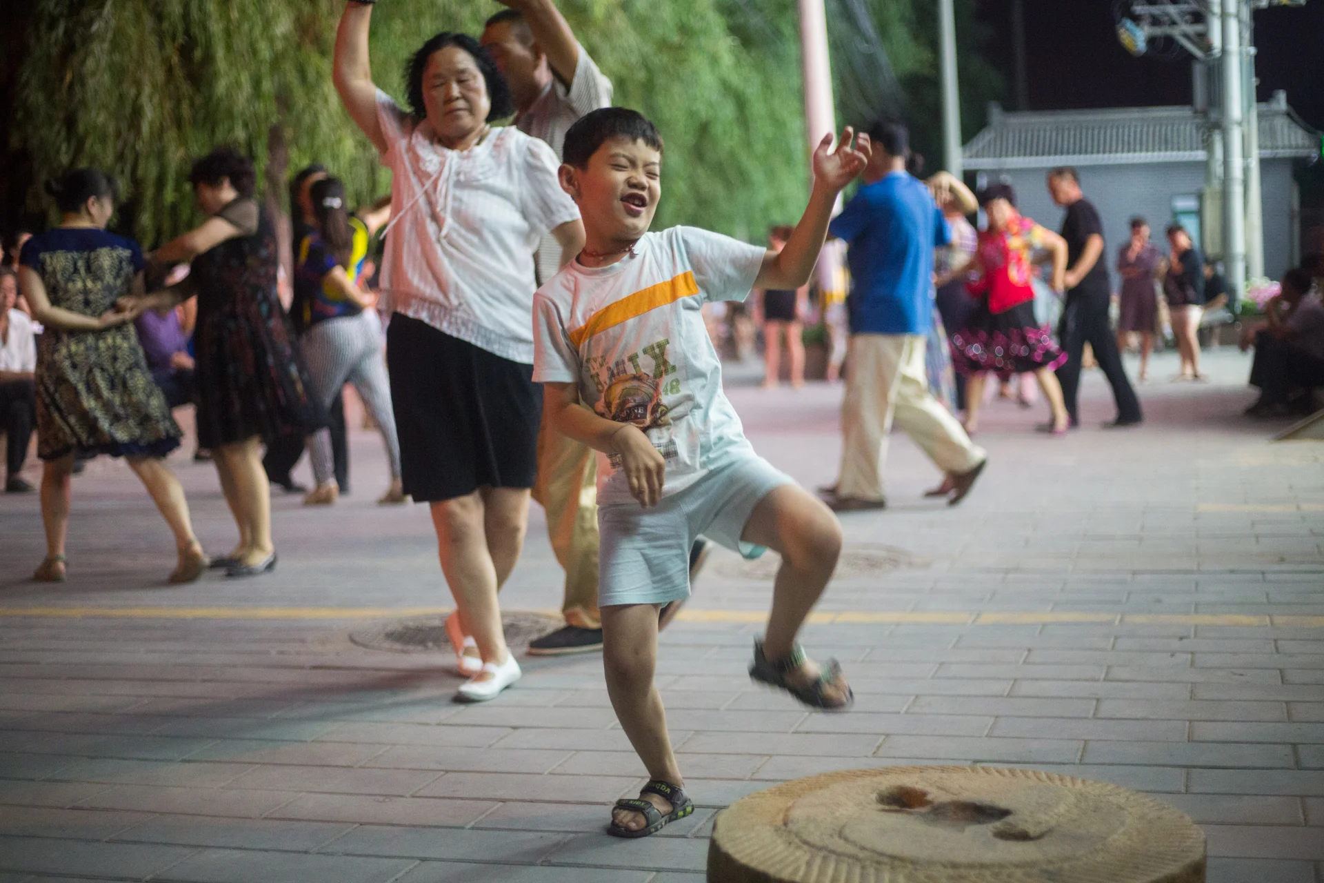  His father watching and laughing outside the frame, a local boy, ignoring the more traditional partner dance, does a more energetic one of his own making.&nbsp; 
