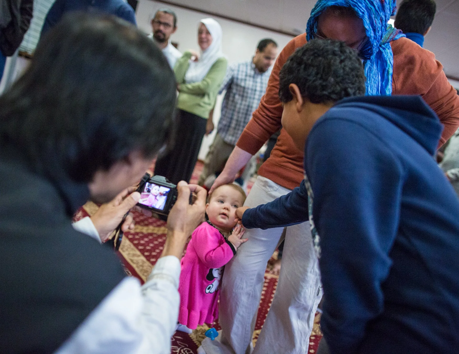 Yojo Surjana, a grad student at Ohio University, snaps a photo as Azzam pinches the cheek of 11 month old Jenevieve White, who clings to her mother, Christa Pratt-Harrington's leg. Christa and Jenevieve visited as part of the local Quaker community 