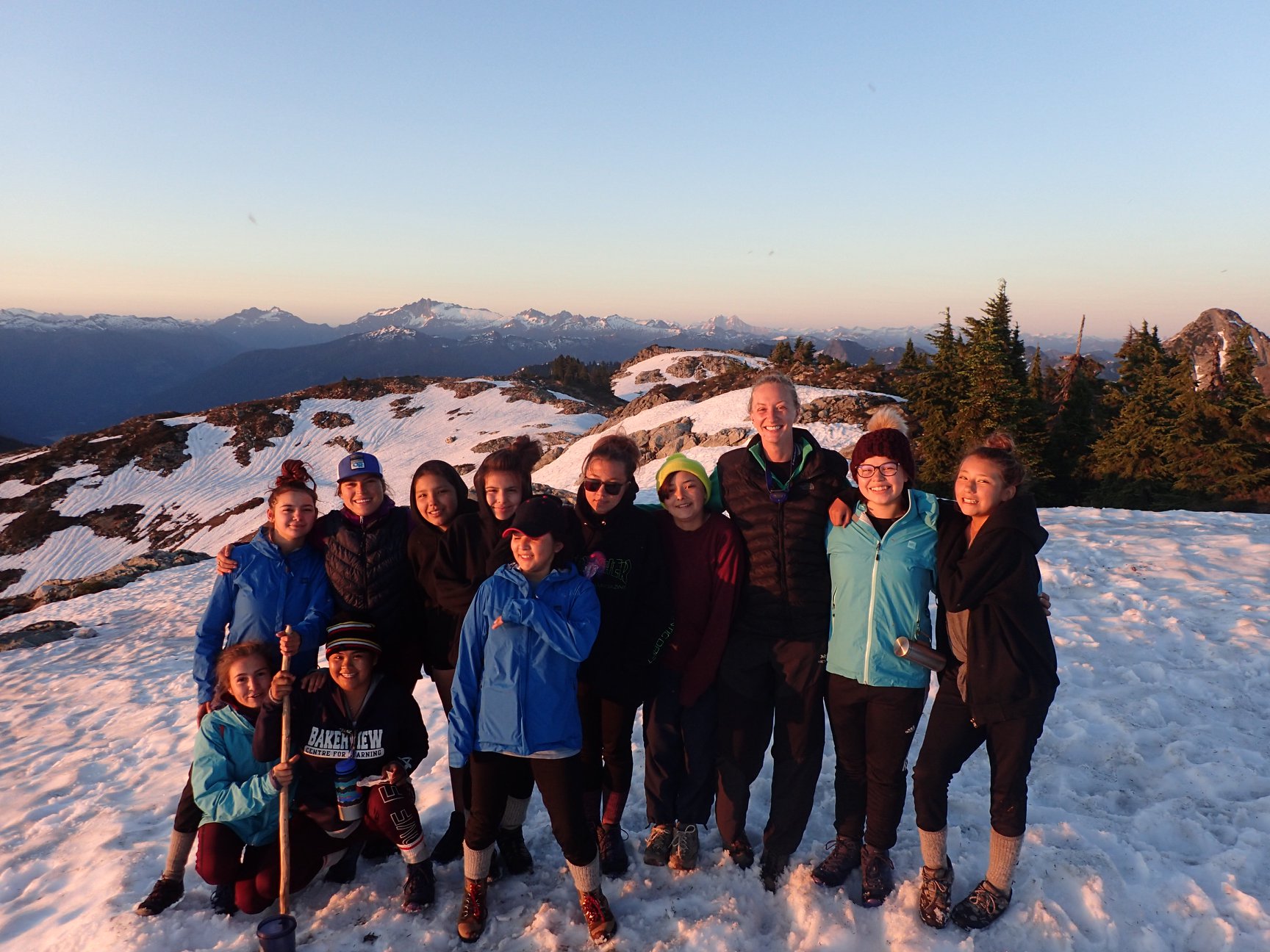  Group photo of 12 smiling girls on top of snowy mountain 