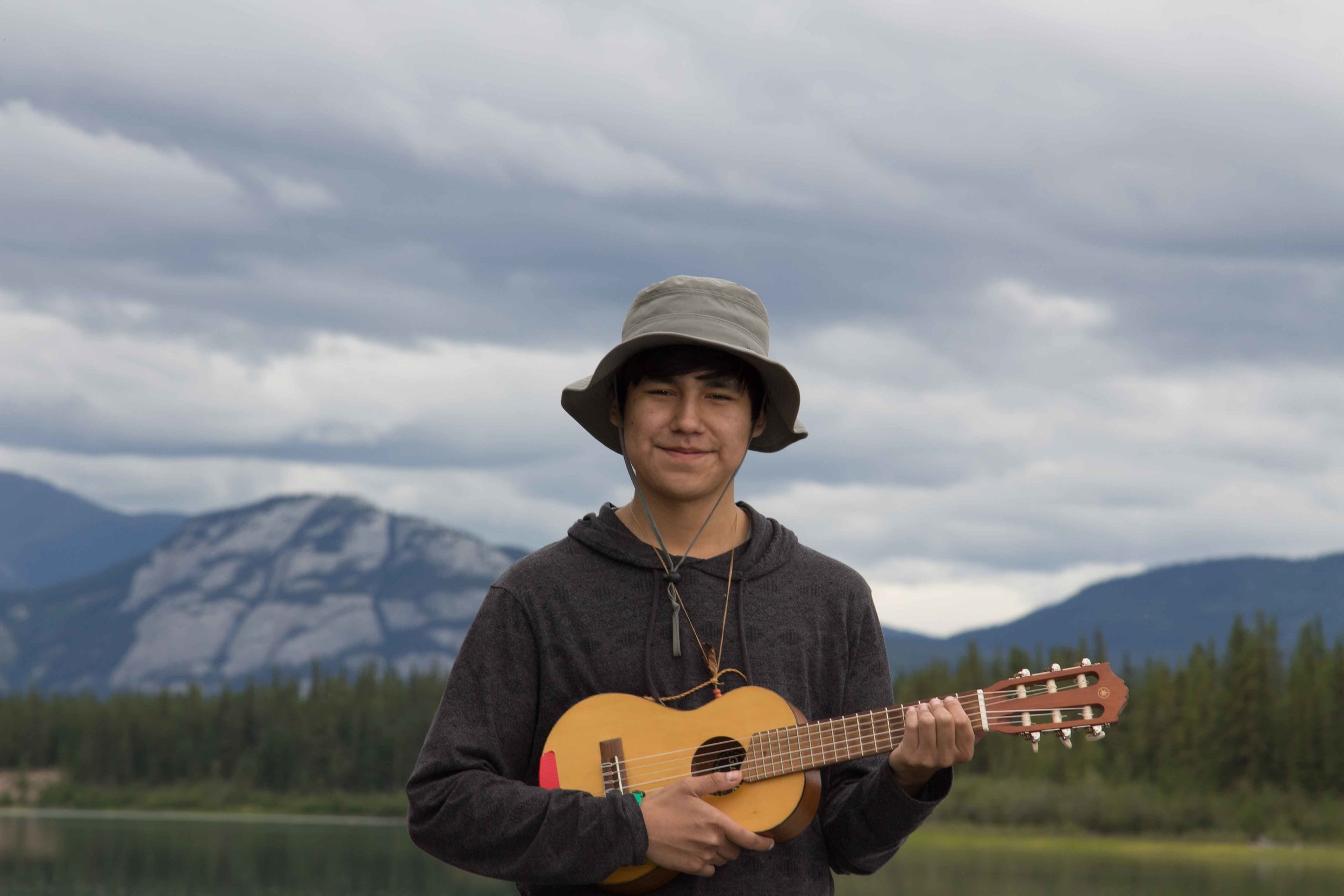  Smiling boy playing the ukelele beside the Yukon River 