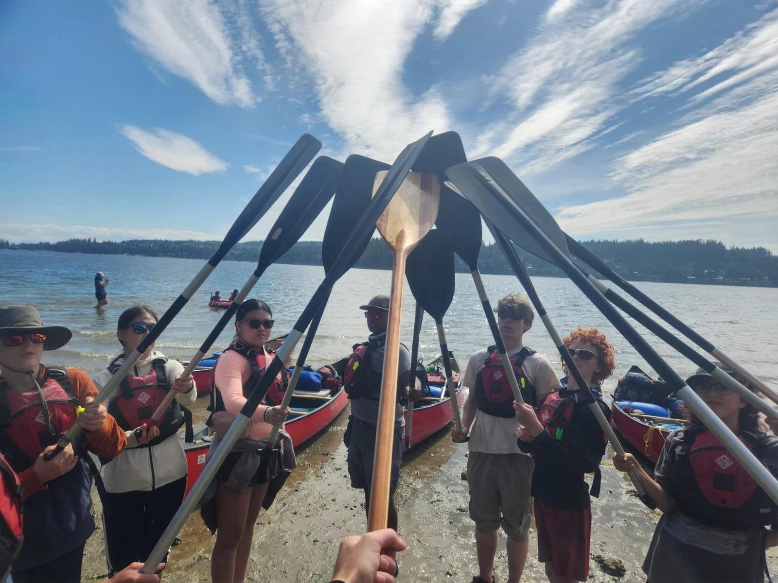 A group of campers touching their paddles together in a circle