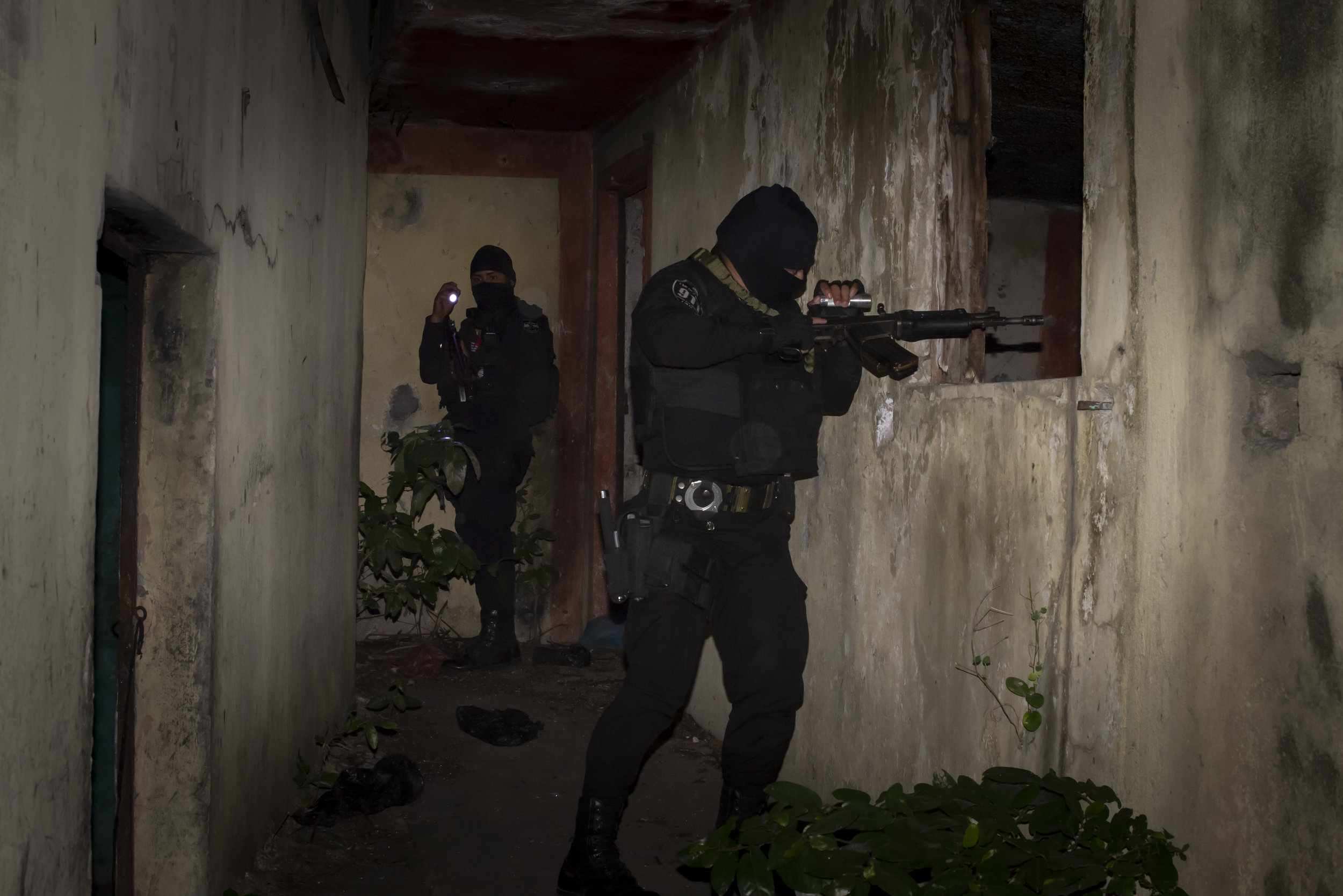 A police officer searching a "destroyer house" in San Salvador, El Salvador. These abandoned buildings are used by gangs to torture and murder rival gang members. 