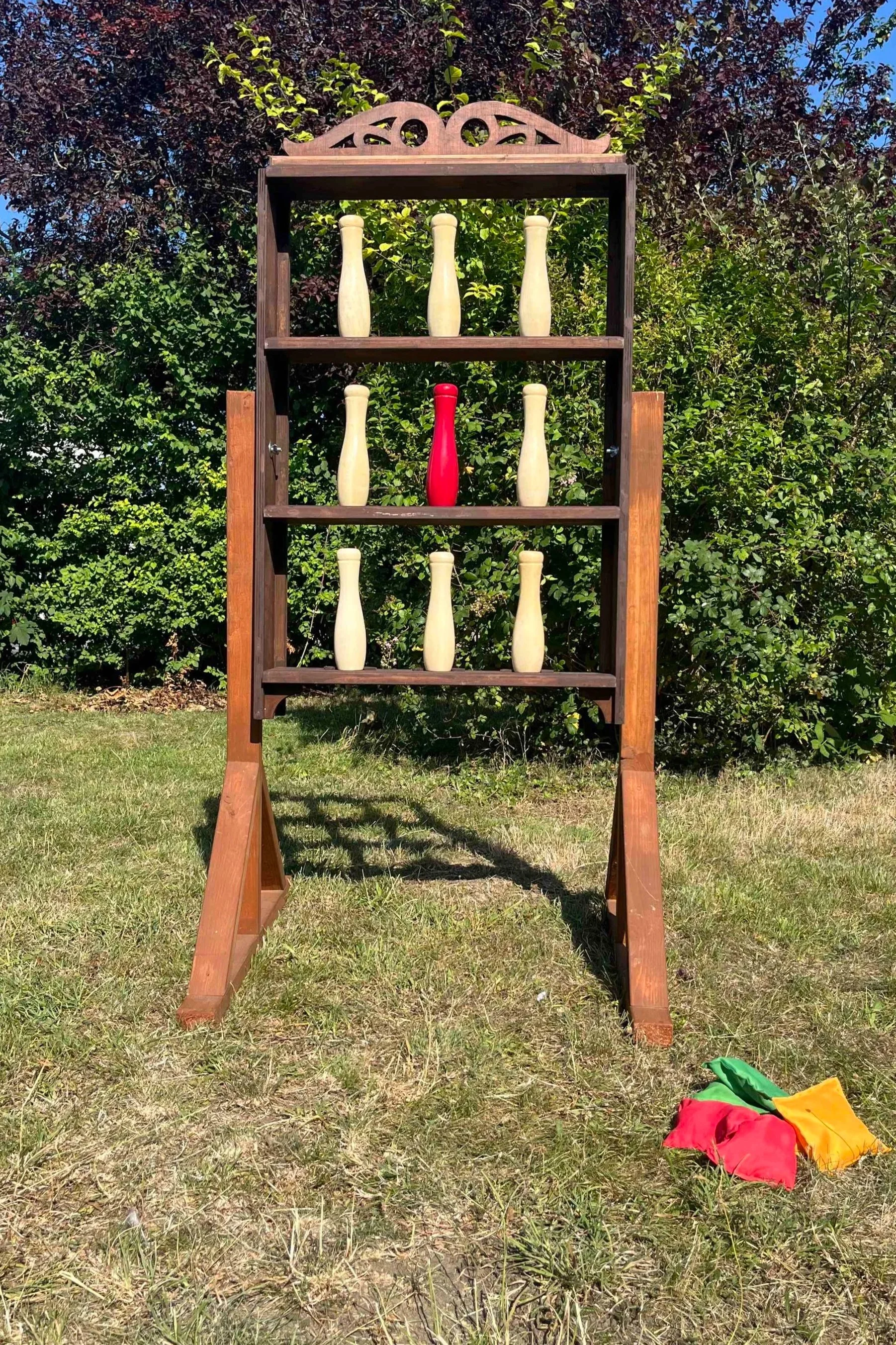 Game with wooden shelves on legs including swirl detail on top, pins on the shelves and bean bags.