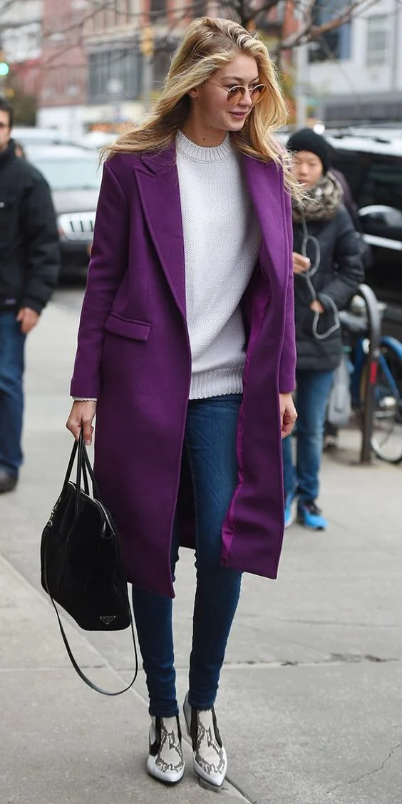 Chic in a long purple coat, cream seater, and snake-print boots