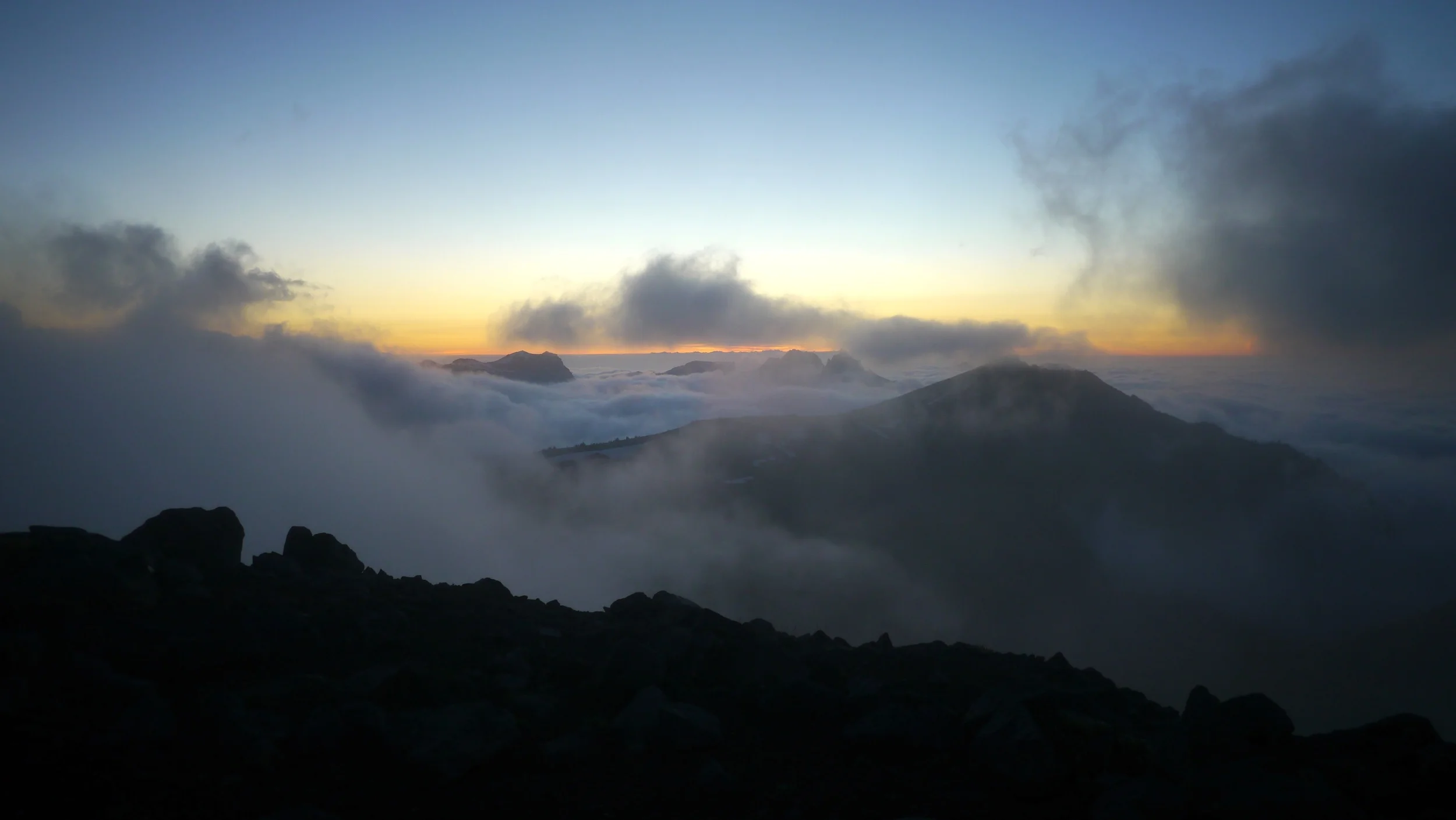 peekaboo views through the clouds and setting sun from Burroughs Mountain