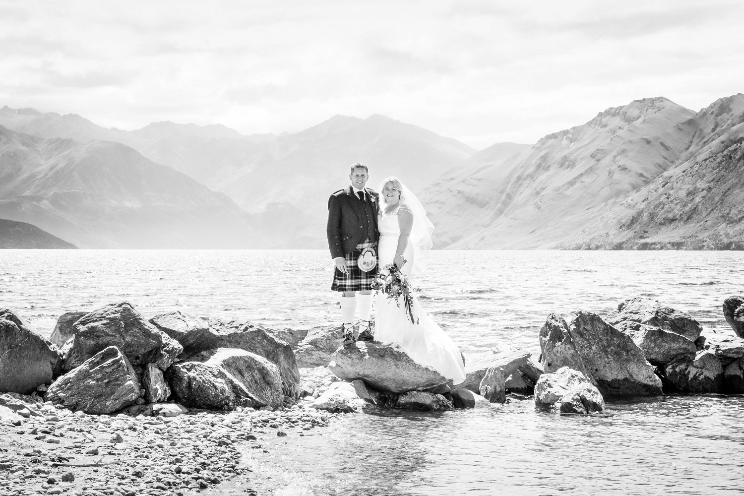 Couple stands on rocks on the Southside if Lake Wanaka