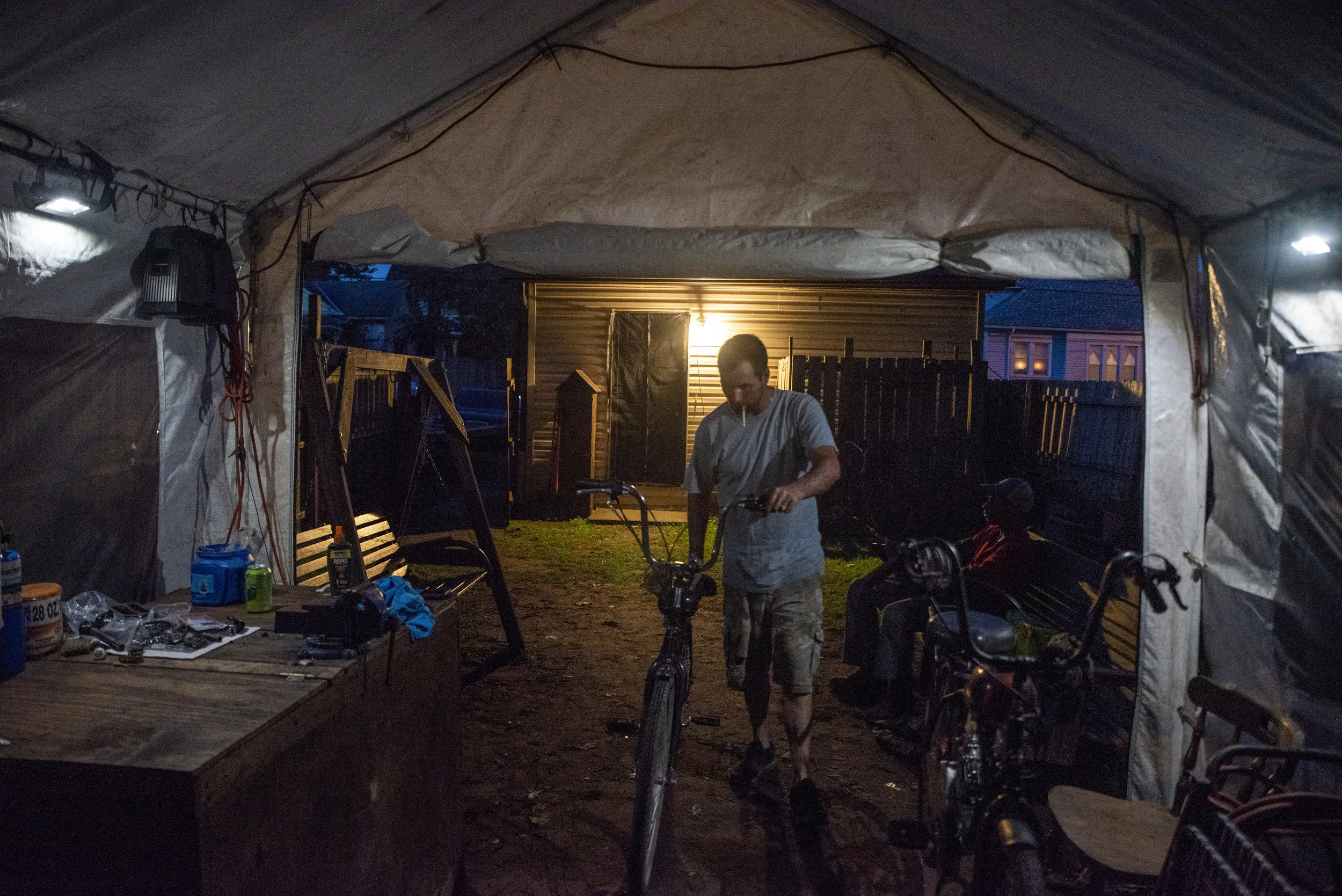 Calvin returns one of the motorized bicycles he was repairing that day to rest in the tent where he stores the rest of his clients' bicycles.