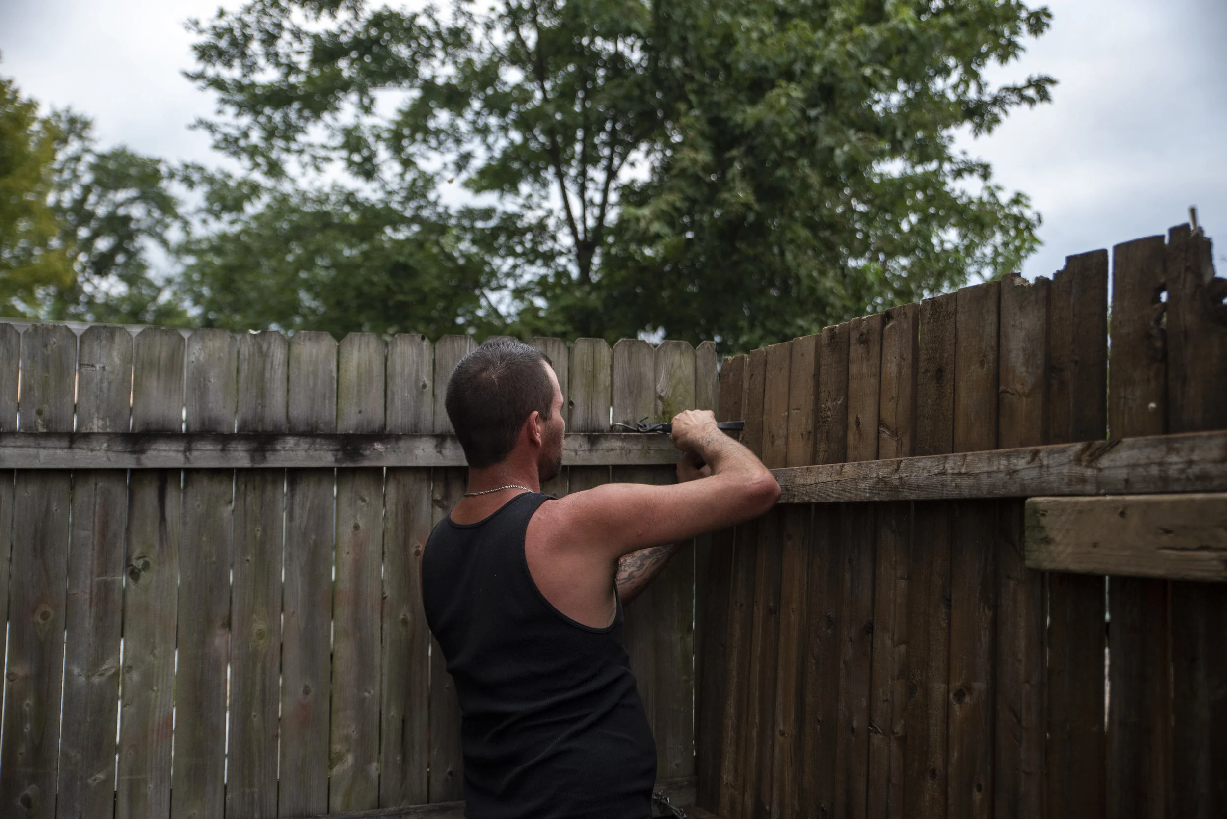 Calvin locks the fence to his backyard each night as he prepares to close up his motorized bicycle shop.
