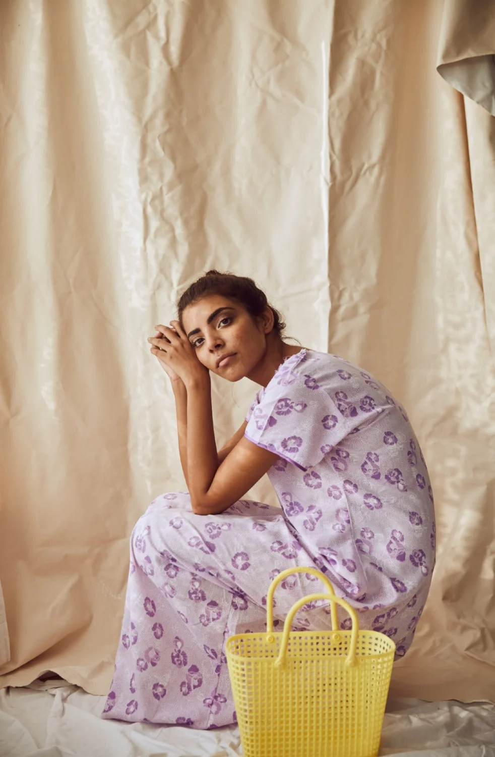 The model wears a soft mauve nightie with a delicately sprinkled tulip pattern and mother-of-pearl buttons, accessorized with a lemon yellow plastic lunch basket.