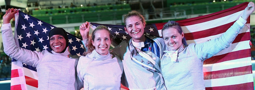 Ibtihaj Muhammad, Mariel Zagunis, Monica Aksamit, and Dagmara Wozniak (L-R) celebrate wit Old Glory after winning a bronze medal in team saber at the 2016 Olympics. (Getty Images)