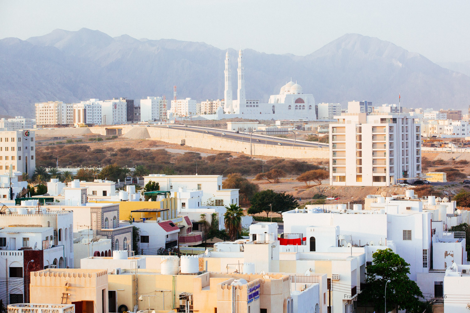 In the early morning, the mosque Saeed Bin Taimur Masjid seen from Ibis Hotel. In the background, the Western Al Hajar Mountains run through the northern coastline of the city.